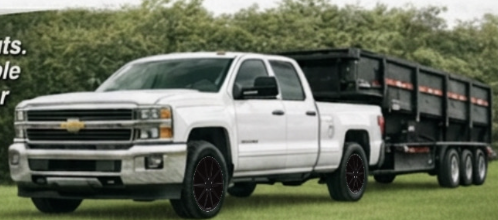 White Chevy 2500 truck pulling a black dump trailer parked on Lee County grass